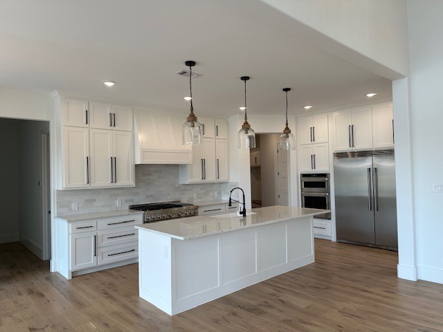 A Pristine White Kitchen Featuring Hardwood Floors and Elegant White Cabinets, Showcasing a Modern and Inviting Atmosphere.